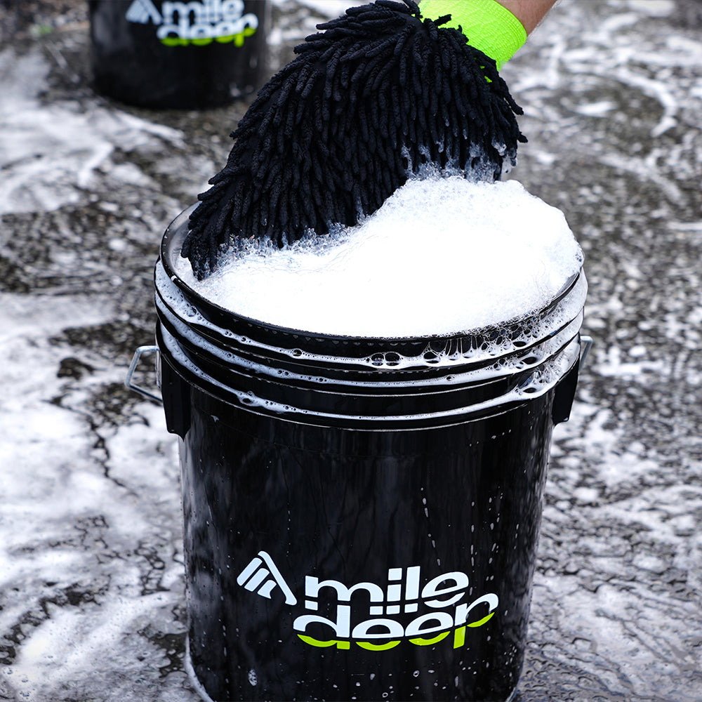 Caress microfibre car wash mitt in black car wash bucket with cleaning solution in.